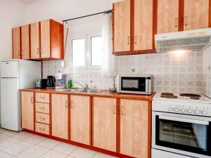 a kitchen with wooden cabinets and a white refrigerator at Luxury Villa in Kalamitsi Alexandrou in Kalamítsion Alexándrou