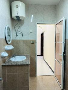 een badkamer met een wastafel en een spiegel aan de muur bij البيت الأبيض للشقق المفروشة White House in Salalah