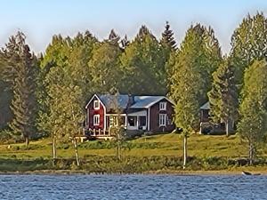 a painting of a house on the shore of a lake at Holiday home BJURHOLM II in Bjurholm