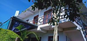 un edificio bianco con balcone e albero di The Train View a Nuwara Eliya