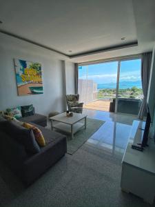 a living room with a couch and a view of the ocean at The Bay Condominium, 1-bed apartment with stunning sea views in Koh Samui 