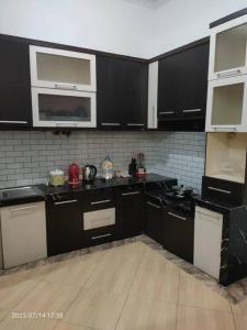 una cocina con armarios negros y electrodomésticos blancos en Homestay Sidoarjo - Comfort en Gedangan