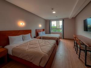 a hotel room with two beds and a desk and a window at MIRAFLORES CITY HOTEL in Lima