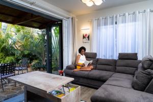 une femme assise sur un canapé avec un ordinateur portable dans un salon dans l'établissement Preety Blue Residence villas, à Grand Baie