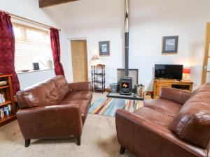 a living room with two leather couches and a fireplace at Stable Cottage in Belford