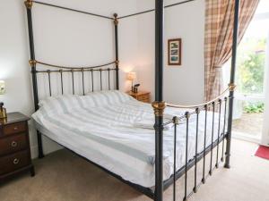 1 dormitorio con cama con dosel negro y ventana en Stable Cottage, en Belford