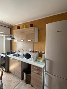a kitchen with a white refrigerator and a microwave at Apartament Central Plaja Modern in Constanţa