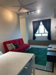 uma sala de estar com um sofá vermelho e um tapete verde em Spice Arena Guesthouse em Bayan Lepas