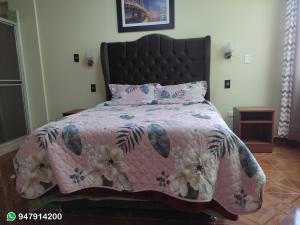 Cama rosa con edredón y almohadas rosas en Hotel ARKONA, en Huancayo