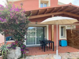 阿格林杜的住宿－Stazzo La Foci appartamenti vista Mare，屋前带雨伞的桌子