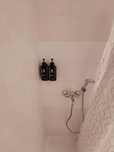 baño con ducha y 2 botellas en la pared en Eleni's Apartments Igoumenitsa -- Γκαρσονιέρα 1ου ορόφου επιπλωμένη, εξοπλισμένη, en Igoumenitsa