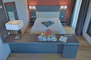 a hotel room with a bed and a table with a tray of food at Zen Hotel Versilia in Marina di Pietrasanta