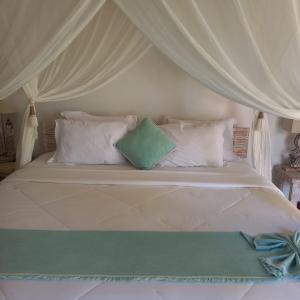 a bed with white pillows and a canopy at Rua Beach Resort Sumba in Rua