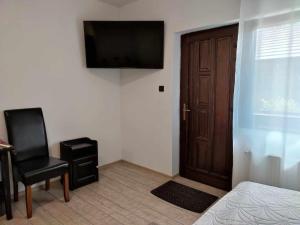 een slaapkamer met een deur, een stoel en een televisie bij Siesta Pension in Miercurea-Ciuc