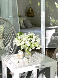 Biały stolik kawowy z wazonem kwiatów w obiekcie Fairytale Inn w mieście Thoddoo