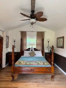 a bedroom with a bed with a ceiling fan at The Red Cottage and Hawaiian Pond Garden Paradise! in Keaau