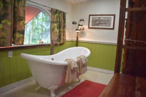 uma banheira numa casa de banho verde com uma janela em The Red Cottage and Hawaiian Pond Garden Paradise! em Keaau