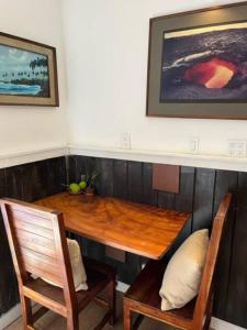 a dining room table with two chairs and a wooden table at The Red Cottage and Hawaiian Pond Garden Paradise! in Keaau