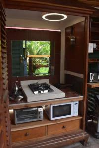 a kitchen with a stove and microwaves on a counter at The Red Cottage and Hawaiian Pond Garden Paradise! in Keaau