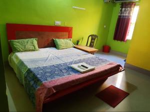 Schlafzimmer mit einem Bett mit rotem Kopfteil und grünen Wänden in der Unterkunft Goroomgo Sun Plaza Lodge konark in Konark