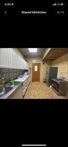 a large kitchen with white cabinets and a refrigerator at Private Room in shared Apartment in Abu Dhabi