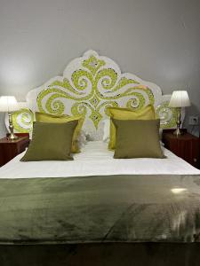 a bedroom with a large bed with green and yellow pillows at Rabbit Hole Hotel in Krugersdorp