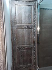 Una puerta de madera en un baño junto a una ducha. en Relax al Mare en Olbia