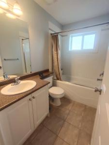 een badkamer met een wastafel, een toilet en een spiegel bij Green Leaf B&B in West Kelowna