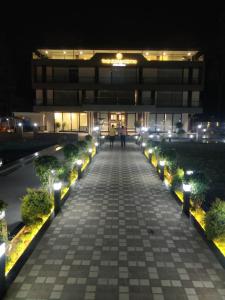 a building at night with people walking down a sidewalk at Green Icon Hotels & Resorts in Kandogal