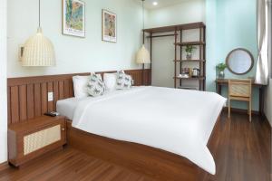 a bedroom with a large white bed and a mirror at The Backpacker Hostel and spa in Da Nang