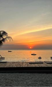 zachód słońca nad oceanem z łodziami w wodzie w obiekcie My Blue Hotel Zanzibar w mieście Nungwi