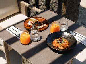 a table with two plates of food and glasses of orange juice at Elysian Retreat in Oia
