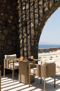 a patio with a table and chairs next to a stone wall at Elysian Retreat in Oia