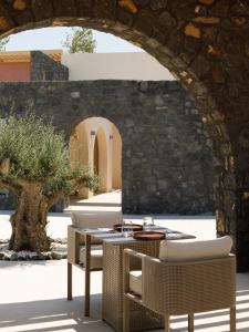 a table and chairs in front of a stone wall at Elysian Retreat in Oia