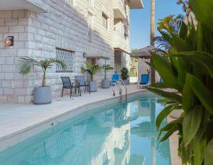 a swimming pool with chairs and tables next to a building at Dar Al Mauge Boutique Hotel with Outdoor Pool in Bethlehem