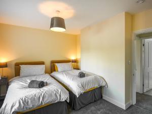 two beds in a room with yellow walls at Pickle Cottage in Church Stretton