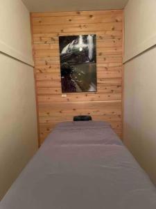 Cama en habitación con pared de madera en The Groves at Redway Beach - Studio, en Redway