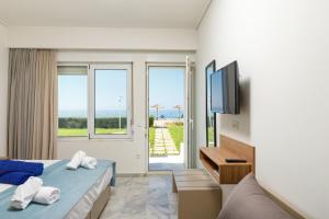 a hotel room with a bed and a tv and windows at Kostakis Beach in Gerani Chanion