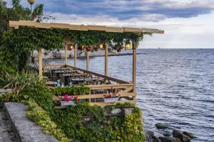 a restaurant with tables and chairs next to the water at Oasis dream apartment with pool by the sea in Nesebar