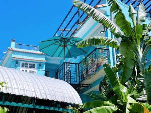 a blue building with a balcony and an umbrella at Quy Phuong - Homestay in Tân Hiệp