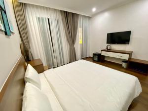 a bedroom with a white bed and a flat screen tv at MOONLIGHT HOTEL in Ha Long