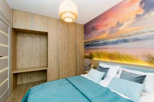 1 dormitorio con 1 cama con una pintura en la pared en Apartamenty Baltic Island en Gdansk