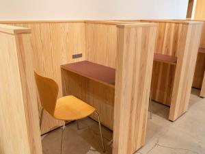 a wooden desk and a chair in a room at Hotel Plus Hostel SAPPORO in Sapporo
