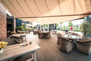 ein Restaurant mit Tischen und Stühlen und einem großen Sonnenschirm in der Unterkunft Fasson Hotel in Heede