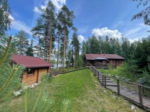 a log cabin in the woods next to a wooden fence at Villa Joutsen with jacuzzi in Vuoriniemi