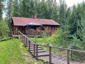 a log cabin with a wooden walkway in front of it at Villa Joutsen with jacuzzi in Vuoriniemi