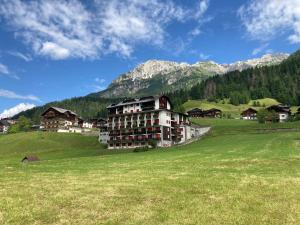 a large building in a field with mountains in the background at Casa Isotta Sappada in Sappada