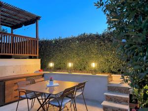 a table and chairs on a patio with a hedge at Villa SOANNE in Bagnols-en-Forêt