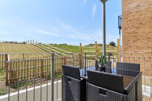 uma varanda com duas cadeiras e uma mesa com uma planta em Stunning 3 Bed Apt With Countryside Views & Parking - Ideal For Families, Groups & Business Stays - Close To Ventnor, Shanklin & Sandown em Ventnor