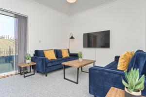 a living room with blue couches and a tv at Meadow View - A Beautiful 3 Bed Apt With Stunning Countryside Views & Parking - Close To Ventnor, Shanklin & Sandown - 5 mins To Beach - Ideal For Friends, Families, & Business Stays - Dog Friendly - 17 in Ventnor